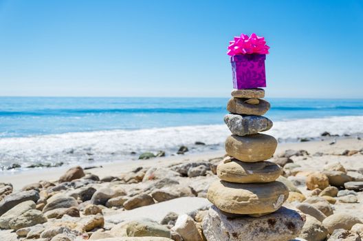Gift box on the top of sea rocks balancing by Pacific ocean 