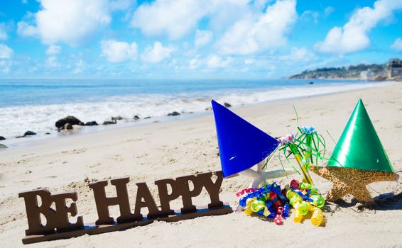 Sign "Be Happy" with Birthday decorations on the beach by the ocean
