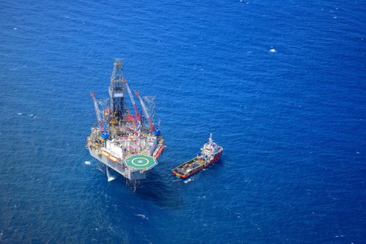 The offshore drilling oil rig and supply boat top view from aircraft.