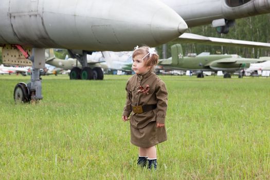 little girl in a military uniform against planes