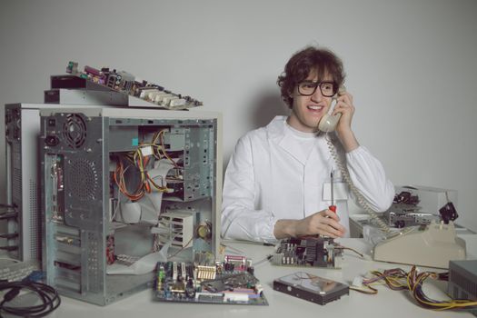 Happy computer technician in his laboratory is talking on the phone