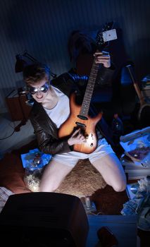 Excited boy playing electric guitar in front of the television