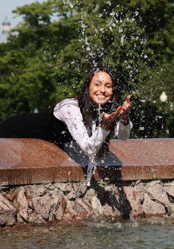 The young beautiful young woman touch fountain hand