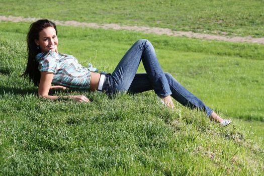 Portrait of young woman lying on a green lawn