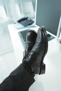 Cropped shot of a manager in office with feet on desk 