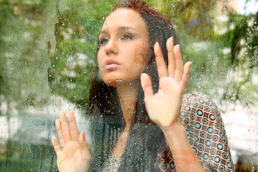 Portrait of a young woman near the window after the rain