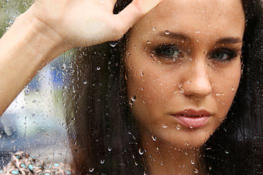 Portrait of a young woman near the window after the rain