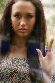Portrait of a young woman near the window after the rain