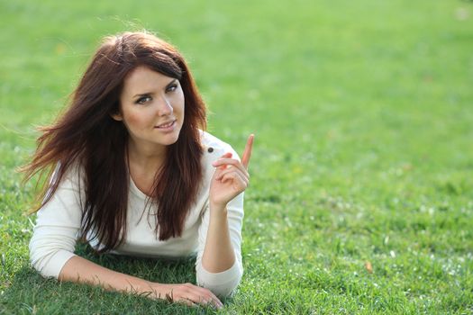 Portrait of young woman lying on a green lawn