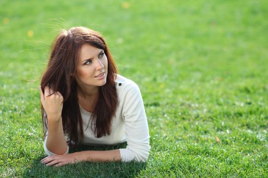 Portrait of young woman lying on a green lawn