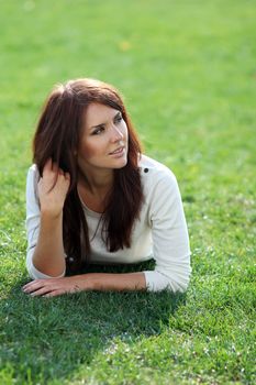 Portrait of young woman lying on a green lawn