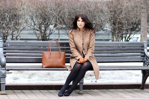 The beautiful young city woman sits on a bench