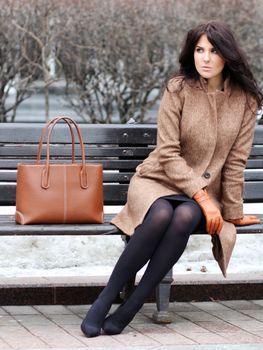 The beautiful young city woman sits on a bench