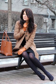 The beautiful young city woman sits on a bench