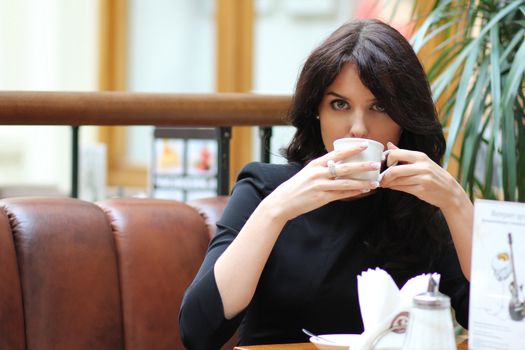 Beautiful young girl sipping coffee