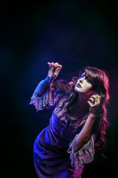 Girl in the image of a witch with a magic wand shot in studio