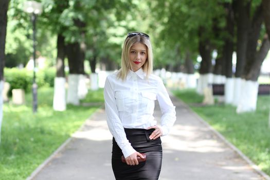 Portrait of young businesswoman standing in sunny park
