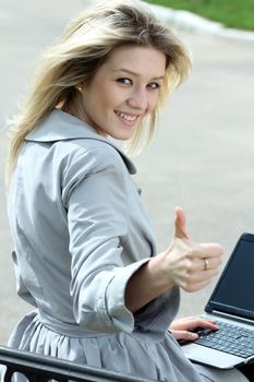 Girl using laptop while sitting on bench at spring park