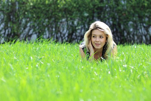 Cute young female lying on grass field at the park
