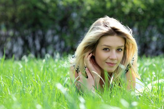 Cute young female lying on grass field at the park