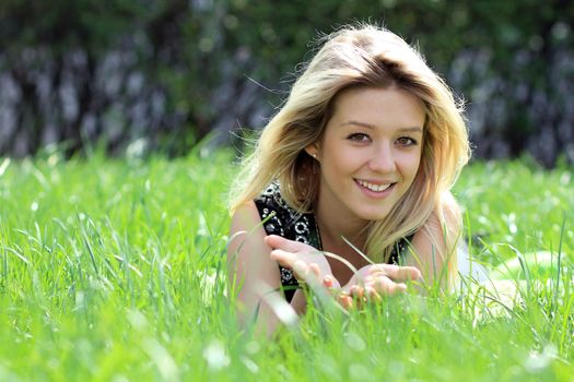 Cute young female lying on grass field at the park
