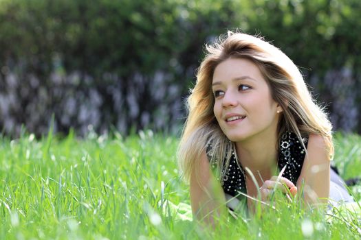 Cute young female lying on grass field at the park