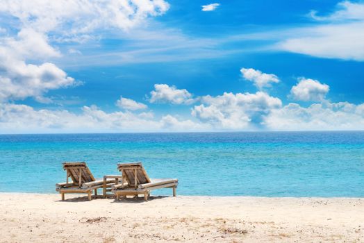 Tropical seascape with bamboo beach beds under blue sky