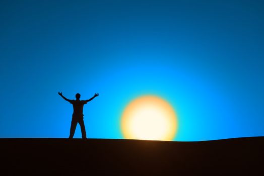 Man at blue background with big sun under horizon with heroic achievement gesture