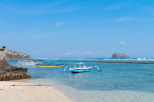 Traditional wooden fishing boats with wings anchored near a Balinese beach