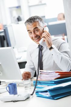 Mature business man talking at phone in office