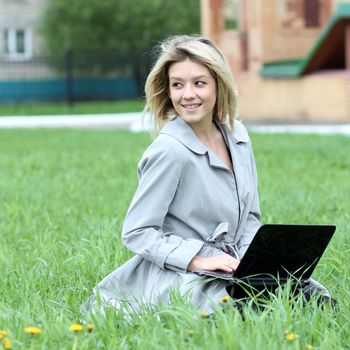 young blond having fun with laptop outdoors