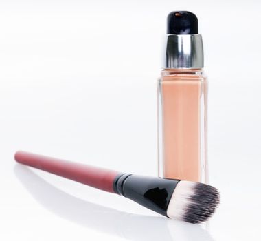 Cosmetic liquid foundation and brush on white background