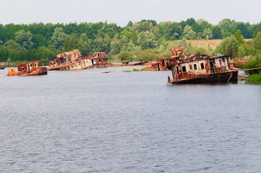 Many wrecked abandoned ship on a river after nuclear disaster in Chernobyl, Ukraine