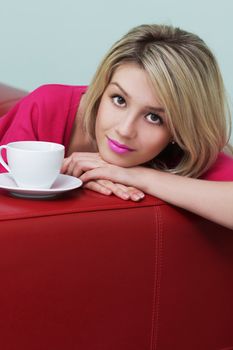 Blonde sits on the couch with a cup of coffee