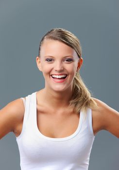 A cute young woman laughing on grey background