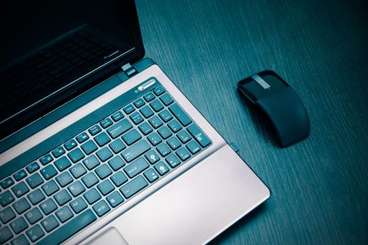 Laptop and modern flat mouse on wooden desk