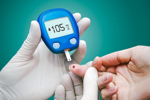 Doctor making blood sugar test. Hands with gloves on medical background