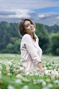 Portrait of young woman sitting on a green lawn