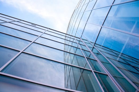 facade of modern glass blue office and sky with clouds reflected