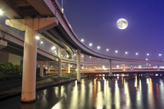  hanged-up highway road over Tokyo bay waters at night time with full moon in the sky