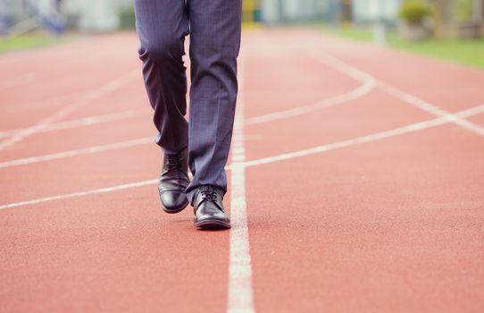 A business man is walking in the running track, close up