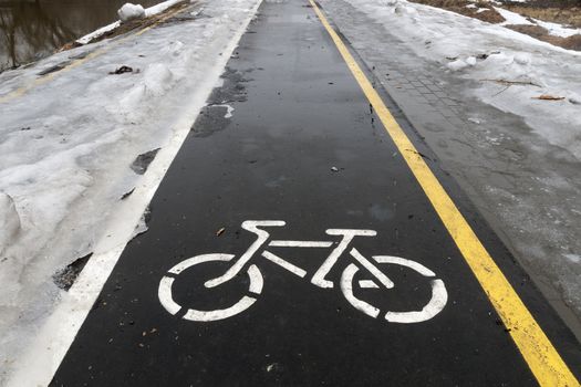 off season on wet bicycle road with snow and ice by both sides