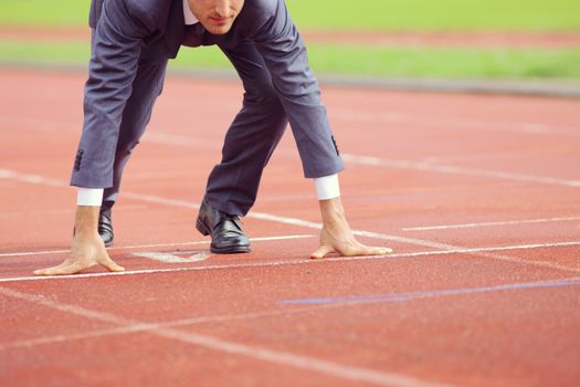 A businessman on a track ready to run 