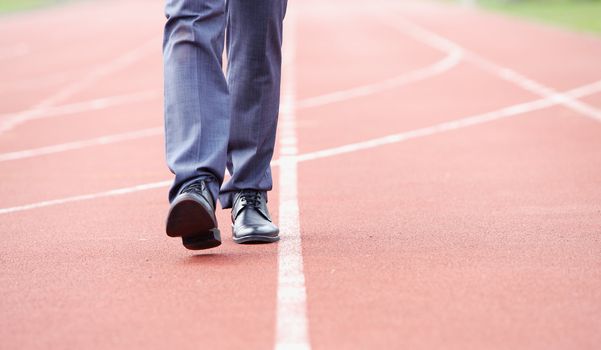 A business man is walking in the running track, close up