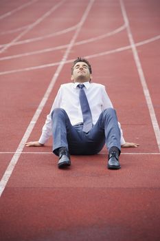 A businessman is sitting on the sports track, conceptual image