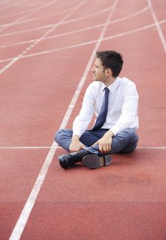 A businessman is sitting on the sports track, conceptual image