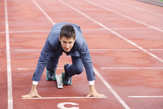A businessman on a track ready to run 