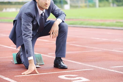 A businessman on a track ready to run 