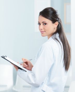 Portrait of a smiling female doctor working on her report 
