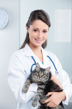 Portrait of a smiling female vet holding a feline 